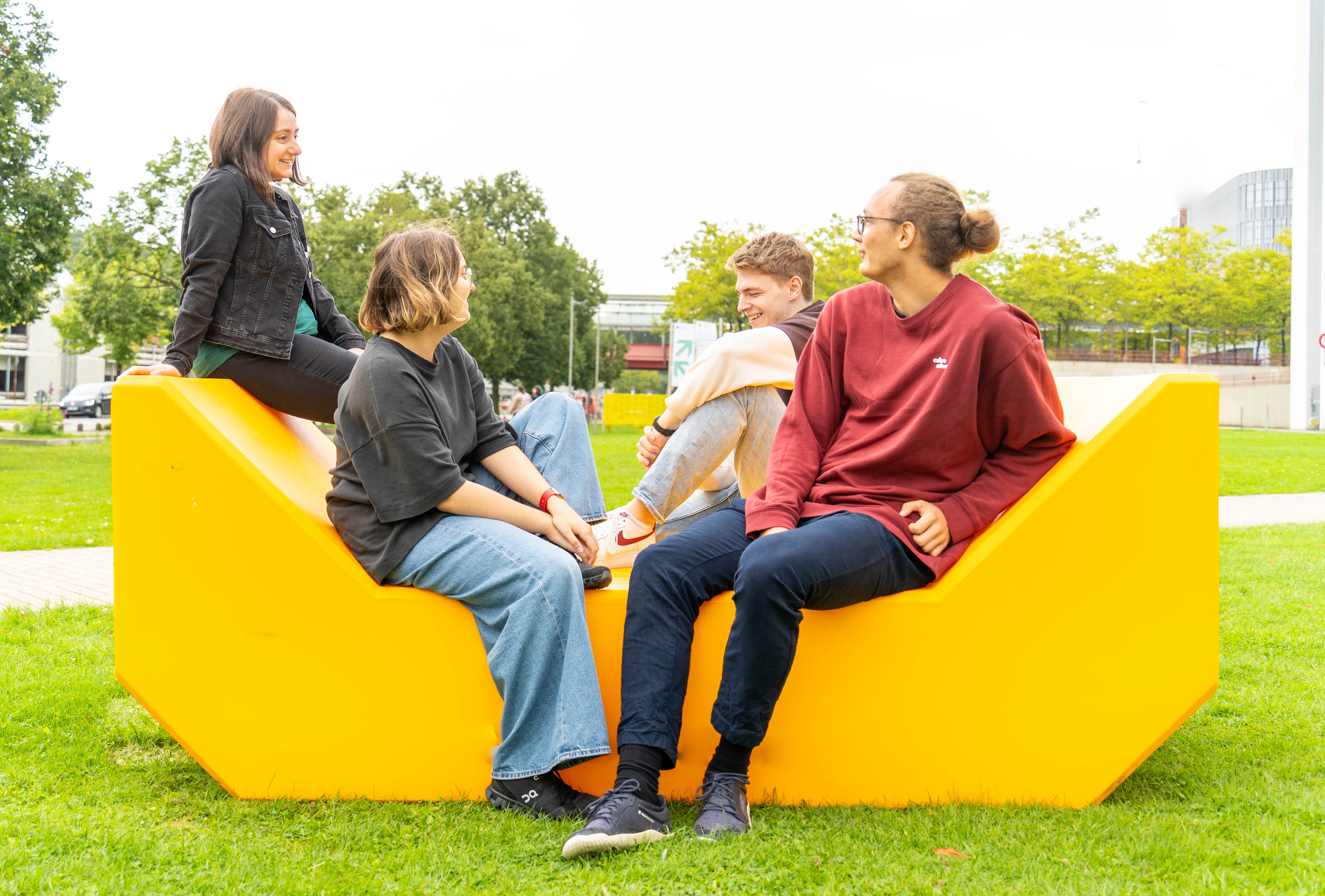 Four staff, people sitting on a yellow piece of seating furniture
