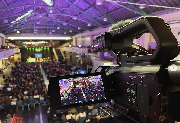 Camera captures a hall filled with people